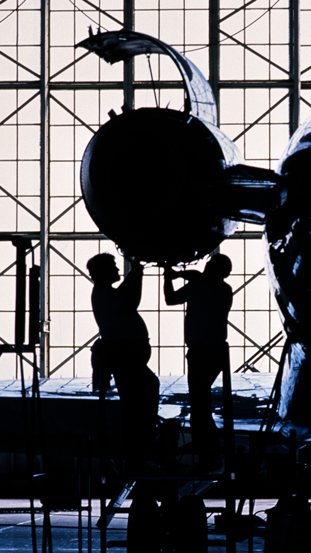 two people working on an airplane engine