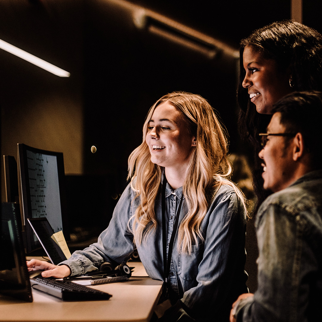 3 people gather around monitor